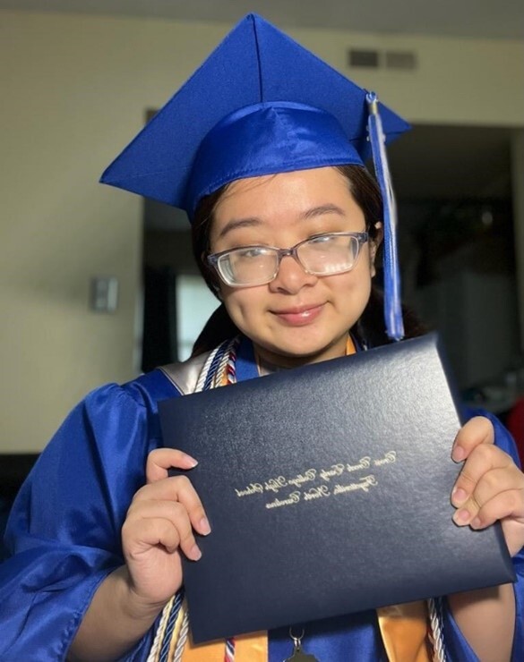 Kristina Nguyen in graduation cap and gown holding diploma.